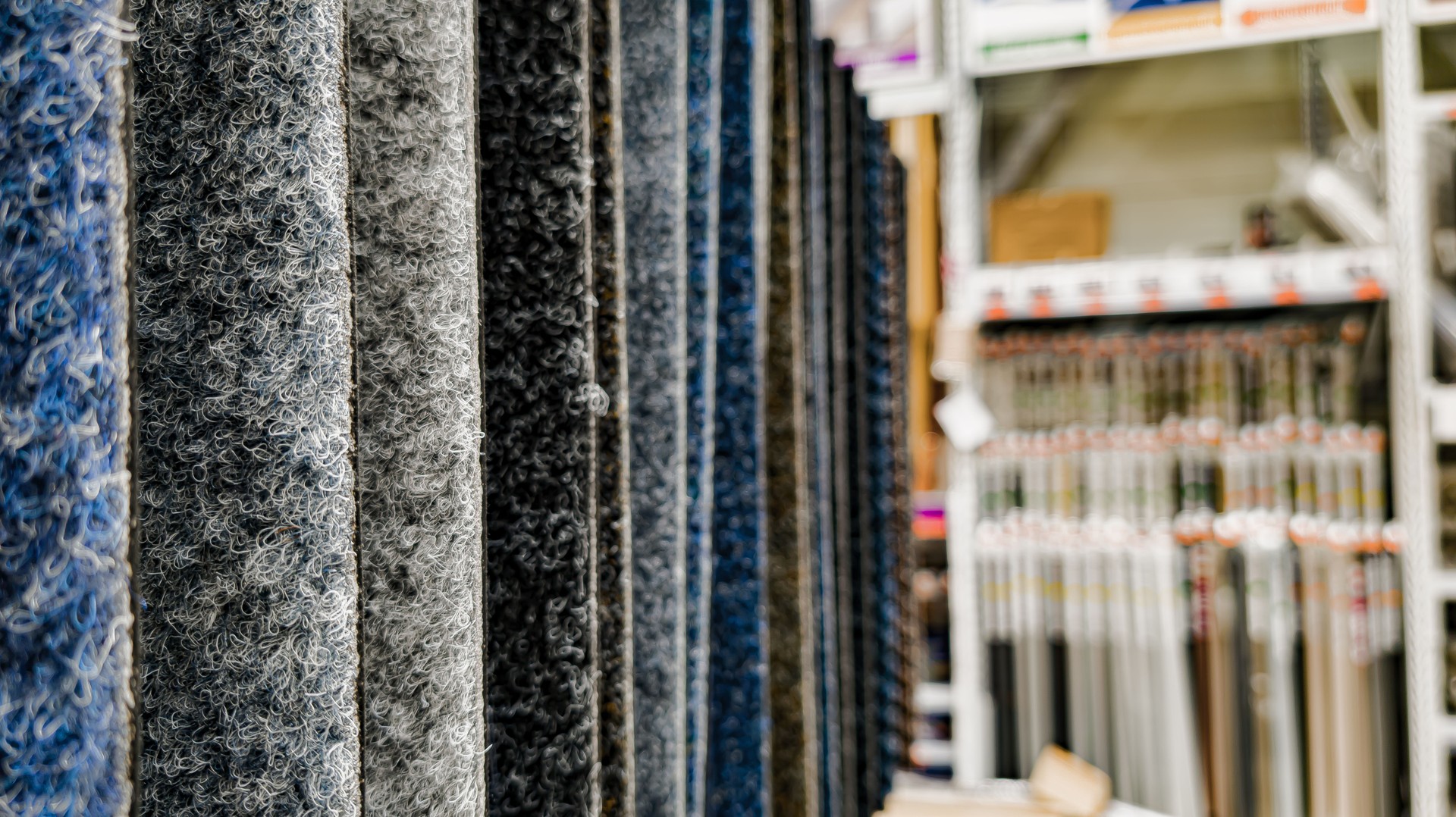 Colorful carpet samples hanging in a row in a hardware store — close-up with blurred background