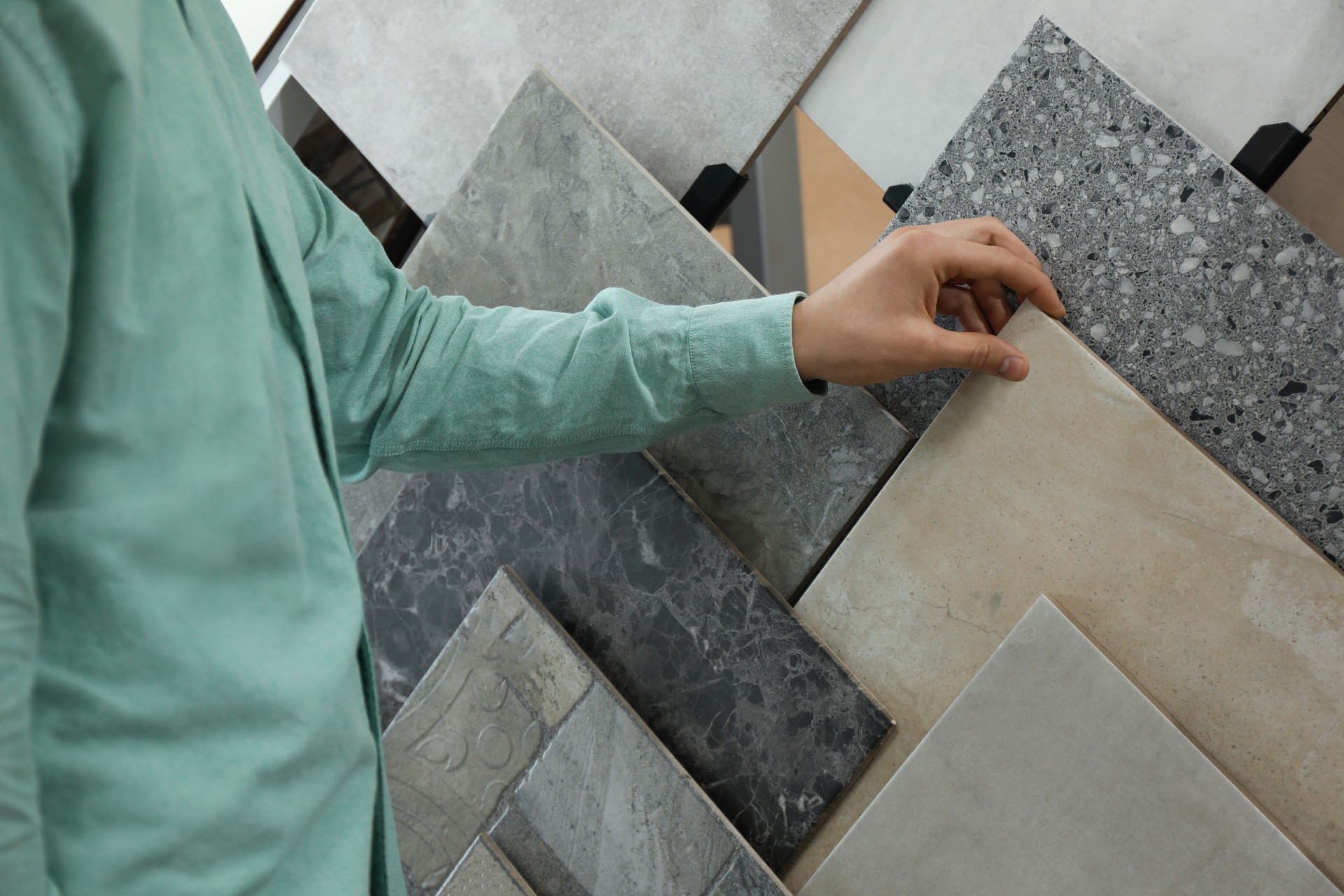 Man choosing tile among different samples in store, closeup