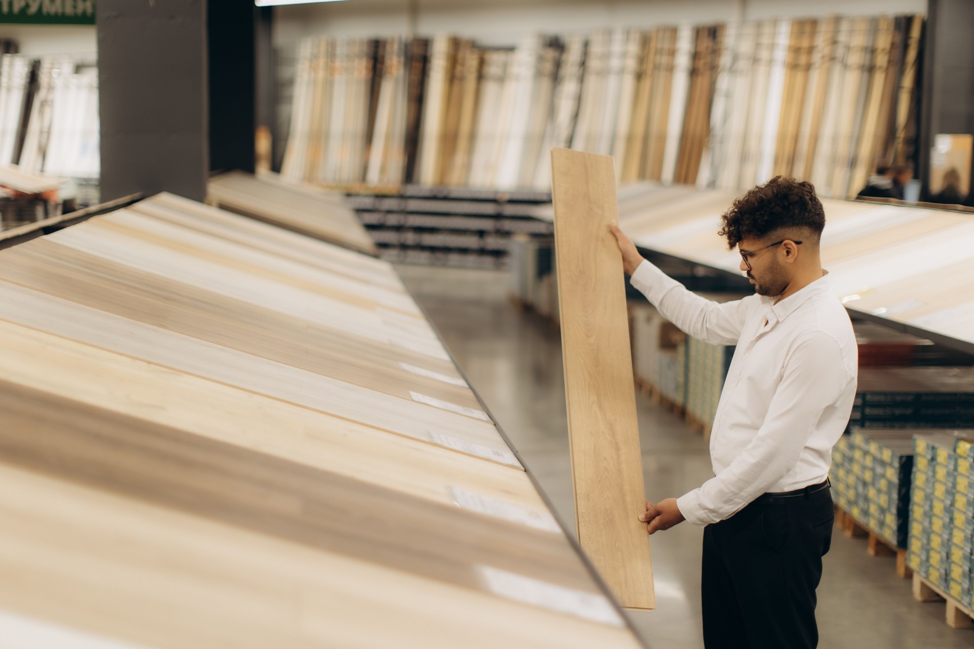 Man Evaluating Wooden Flooring Options in a Commercial Store Setting