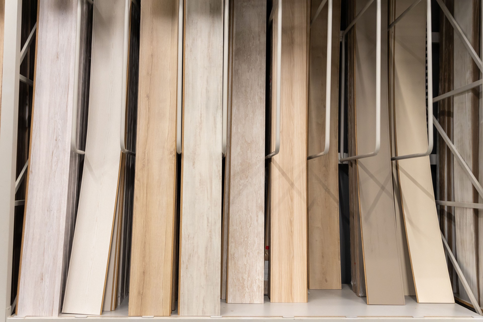 A close-up of various wooden laminate textures and colors displayed on racks in a home improvement store